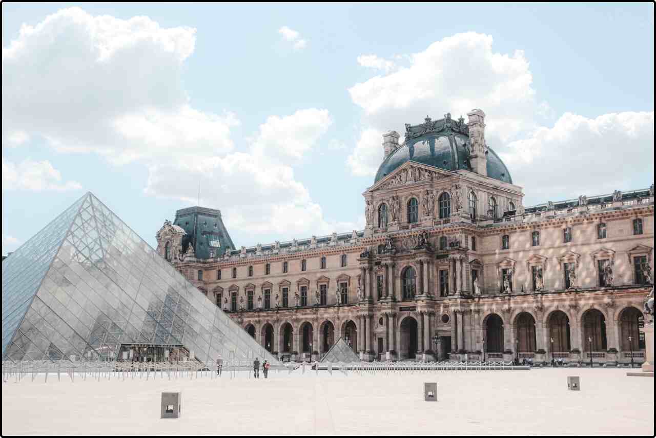 Scenic view of the glass Pyramid at the Louvre Museum, surrounded by historic buildings.